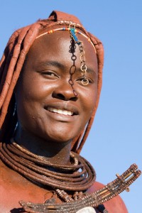 A Himba woman wearing traditional jewellery. The Himba rub red ochre over their bodies, giving them a distinct red colour to their hair and skin.