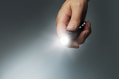 Man's Hand Holding a Small LED Flashlight_131821802