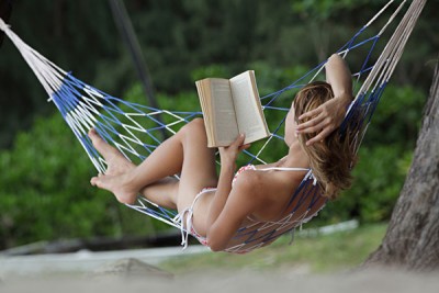 Young Woman Reading a Book Lying in Hammock on Beach_132610445