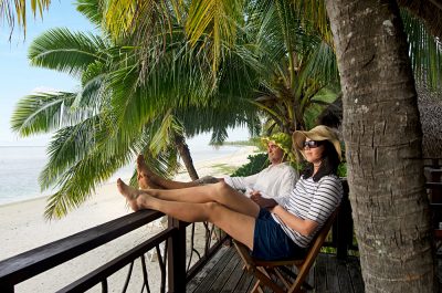 Couple Relaxing on Veranda of Beach Villa, Aitutaki lagoon, Cook Islands