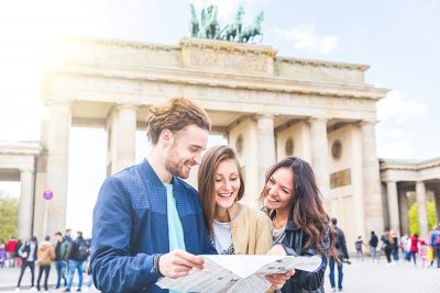 Friends looking at a map with Brandenburg Gate in background, Berlin, Germany