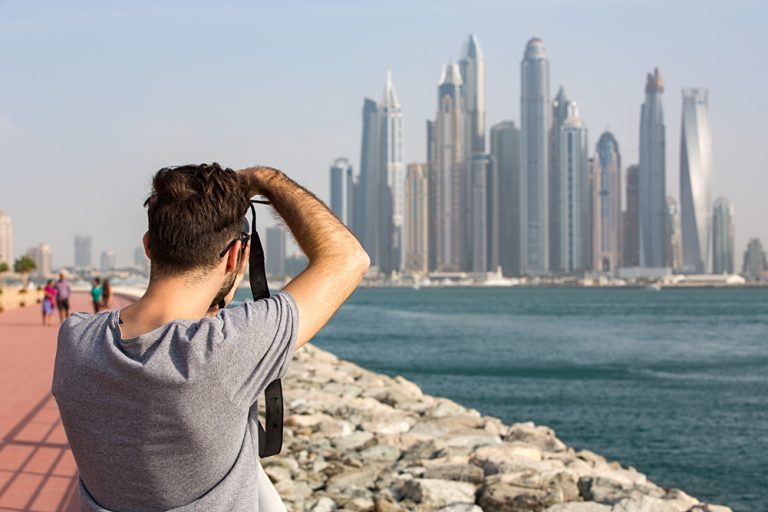 Male Tourist taking photo of the Dubai Marina skyline, United Arab Emirates (UAE)