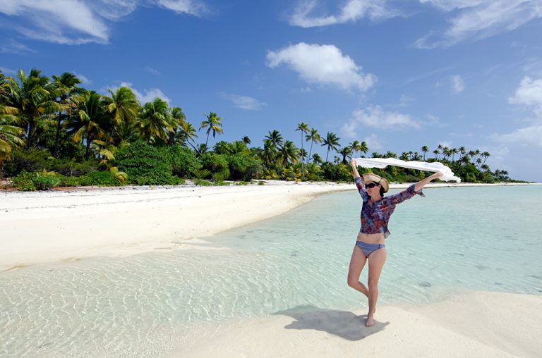 Young woman relaxing on a deserted tropical island in Aitutaki Lagoon, Cook Islands