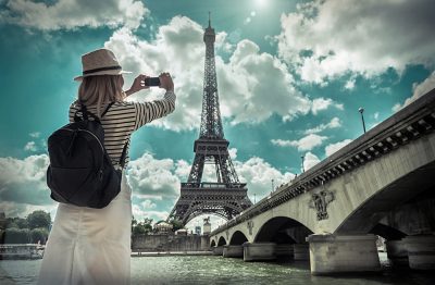 Female tourist photographing the Eiffel Tower in Paris, France