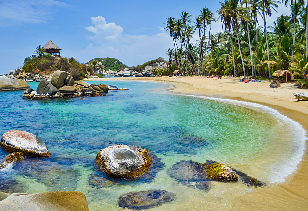 Paradise beach with white sand, palm trees and blue waters of Caribbean Sea in Tayrona National Park in Colombia