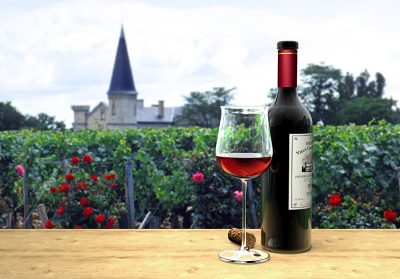 Wine bottle and glass of fictitious Bordeaux red wine with a chateau in the background, Bordeaux, France