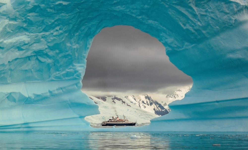 Ship seen through the hole in the iceberg at Antarctic Peninsula, Antarctica