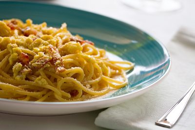 Spaghetti carbonara with egg, smoked bacon and cheese over a table