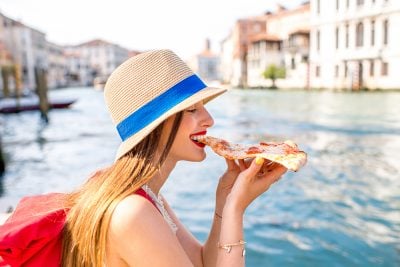 Young Woman eating traditional italian pizza slice, Venice, Italy