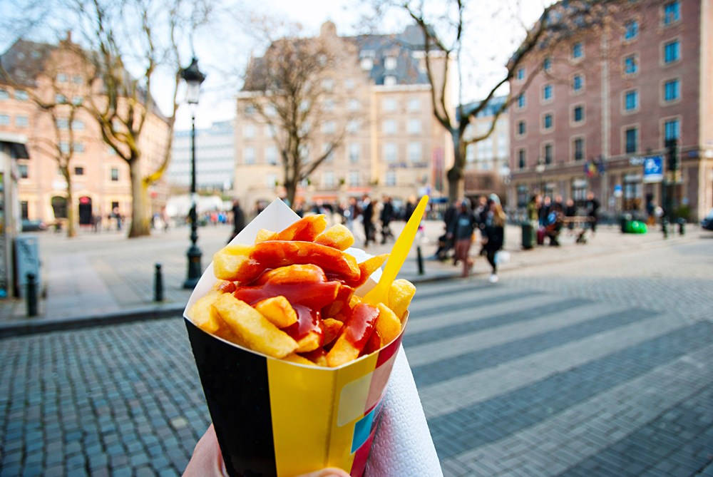 Holding typical Belgian fries in hand in the streets of Brussels, Belgium