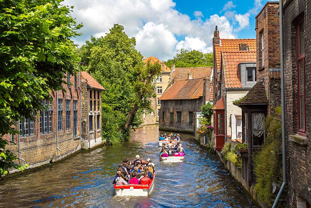 Tourist boat on canal in Bruges on a beautiful summer day, Belgium