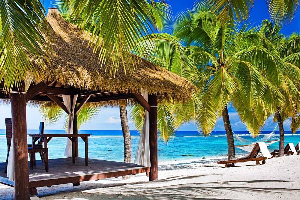 Tropical gazebo with chairs on deserted beach with palm trees, Rarotonga, Cook Islands