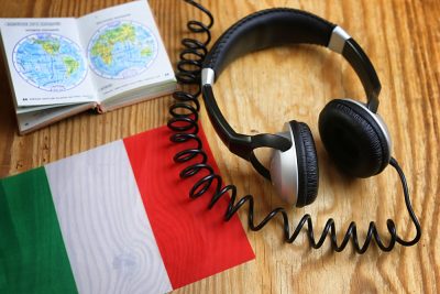 Italian language course headphone and flag on wooden table