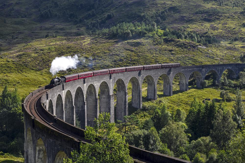 Jacobite steam train on Glenfinnan Viaduct approaching, Highlands, Scotland, UK (United Kingdom)