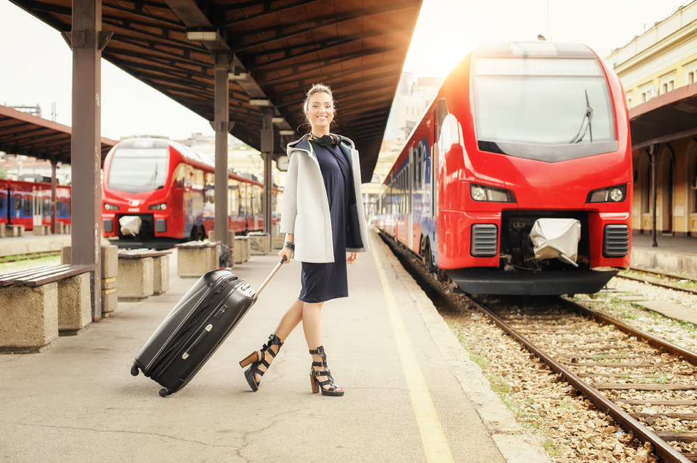 Woman with suitcase standing and posing on the railway station