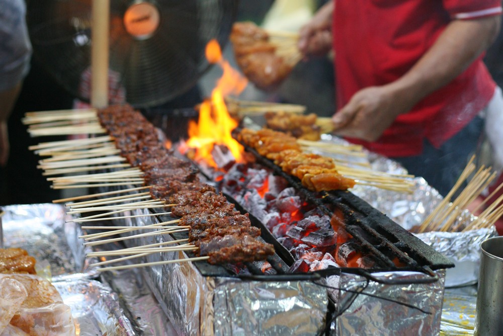 Tasty skewers of chicken cooked over hot coals in Singapore's Satay Street food market, Singapore 