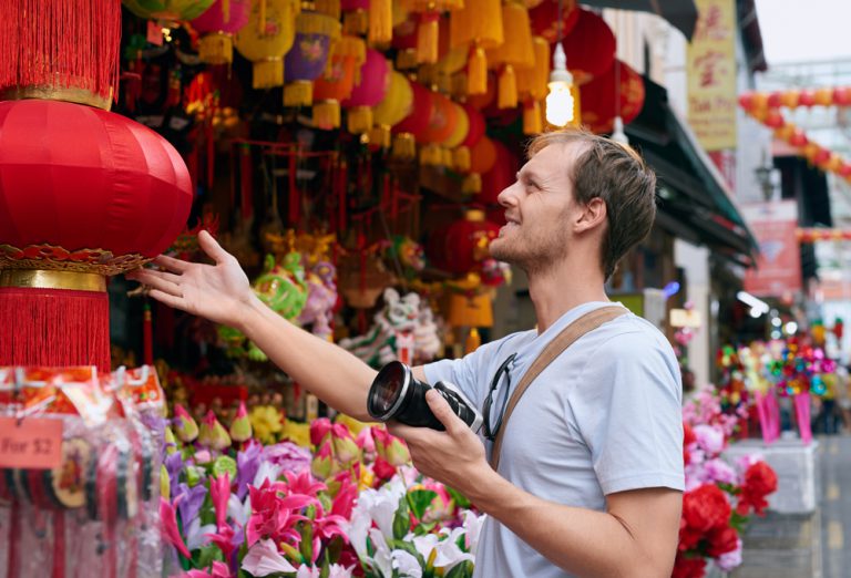 Tourist traveler with camera in modern asian city chinatown shopping looking at a red lantern for souvenir trinkets