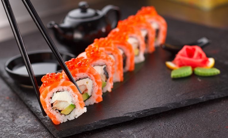 Salmon sushi roll with chopsticks on a stone plate, Japan