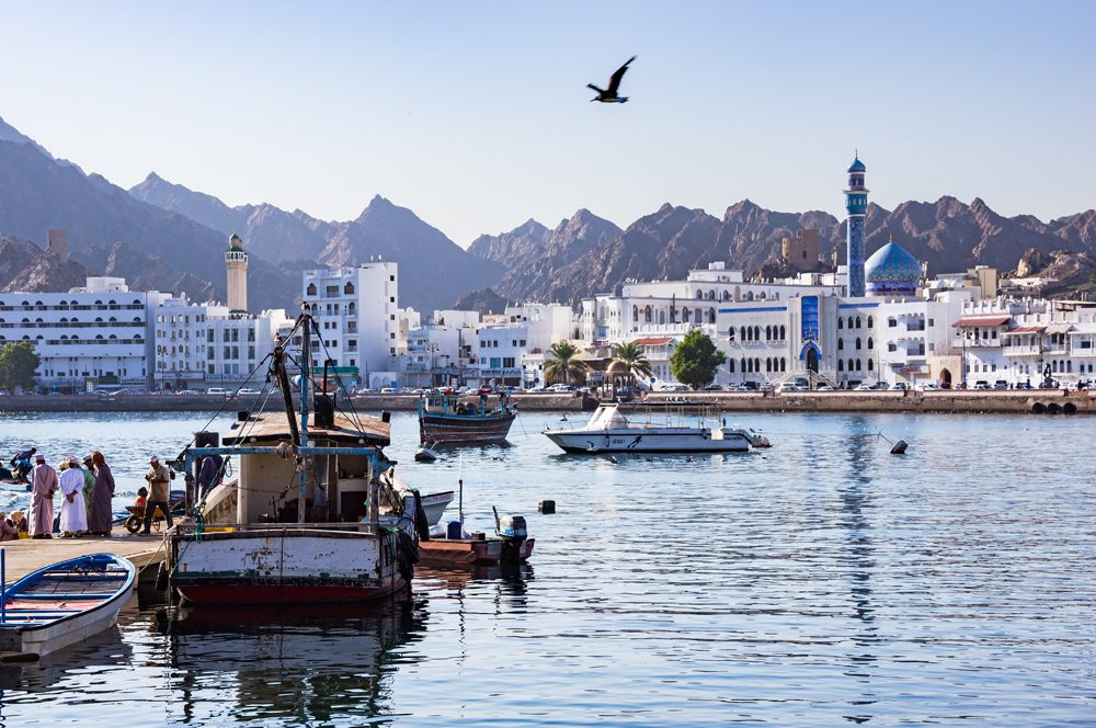 Fishermen at the Muttrah fish docks with Muttrah corniche in the background, Muscat, Oman