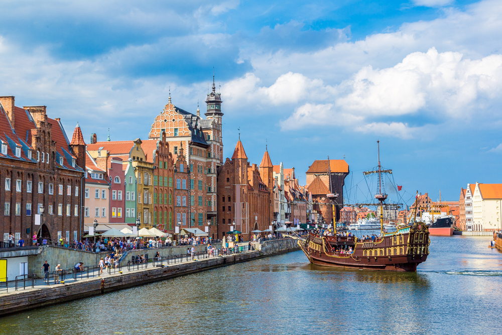 Tourist ship and colourful historic houses reflecting in Motlawa River in port of Gdansk, Poland 