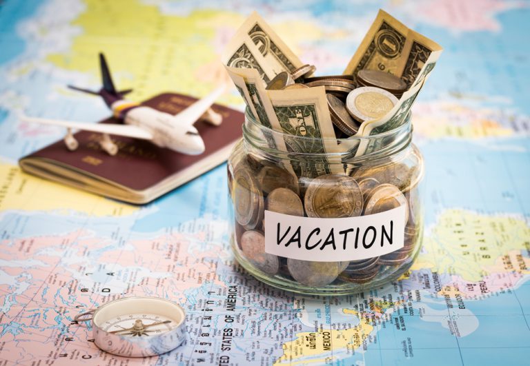 Vacation budget concept with map, small plane, compass, and money jar