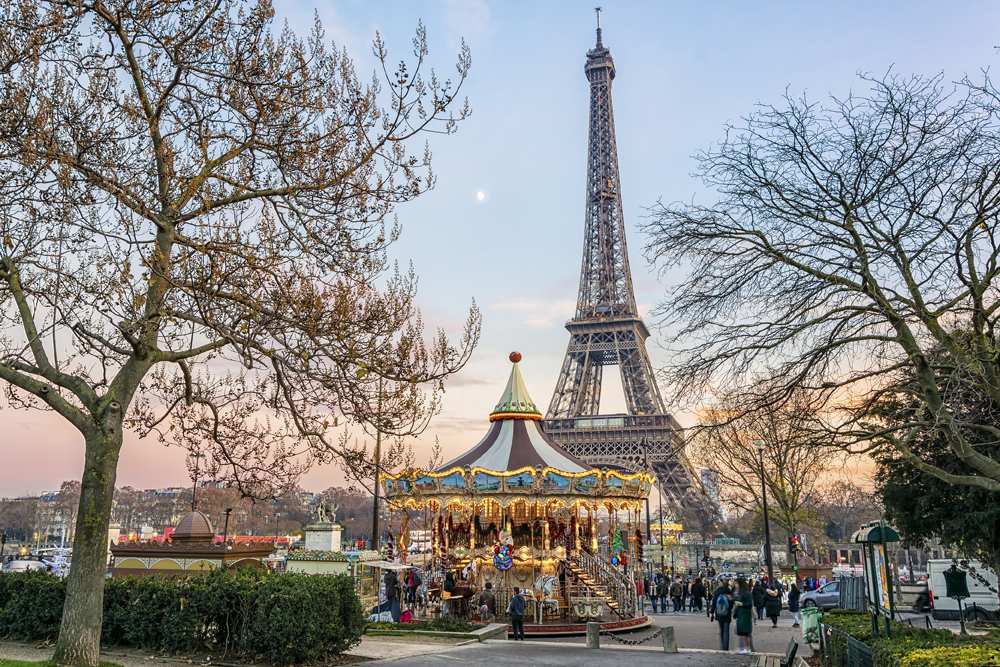 Eiffel Tower and vintage carousel in Paris at sunset in winter, France 