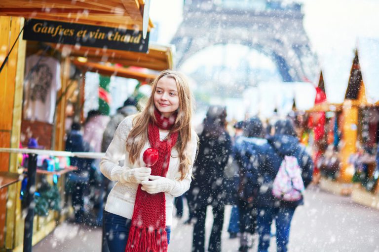 Young girl with caramel apple at a Parisian Christmas market and Eiffel Tower in background at winter, Paris, France
