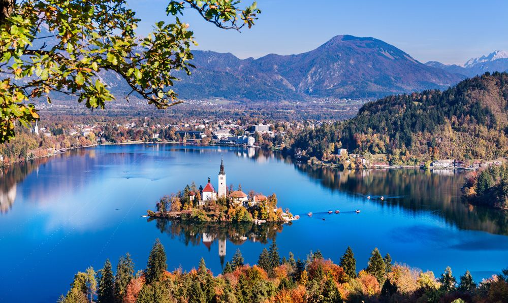 Aerial view of Lake Bled in autumn with Church of the Assumption of Maria and traditional pletna boats, Slovenia Tour