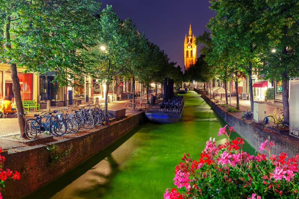 Oude Delft canal and leaning tower of Gothic Protestant Oude Kerk Church at night, Delft, Holland, Netherlands 