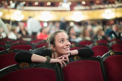 Smiling young woman sitting in auditorium of theatre