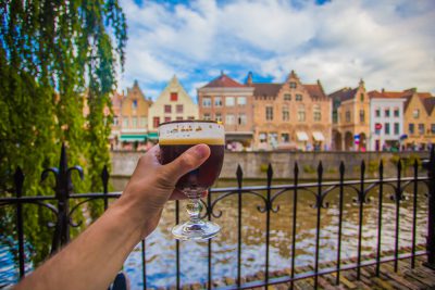 Full glass of beer with Bruges cityscape background, Belgium Vacations