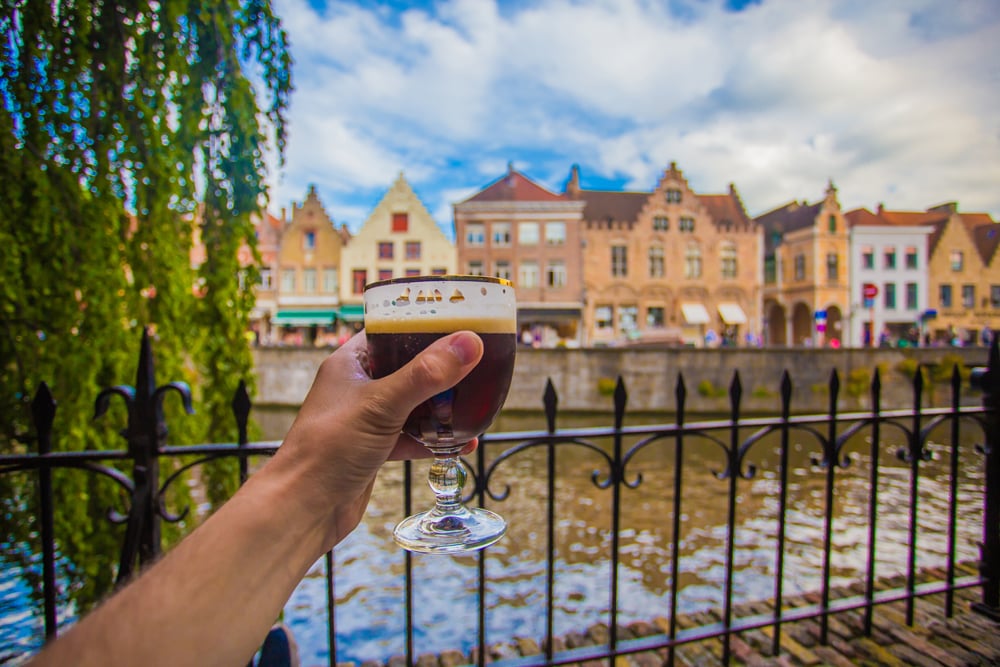 Full glass of beer with Bruges cityscape background, Belgium Vacations
