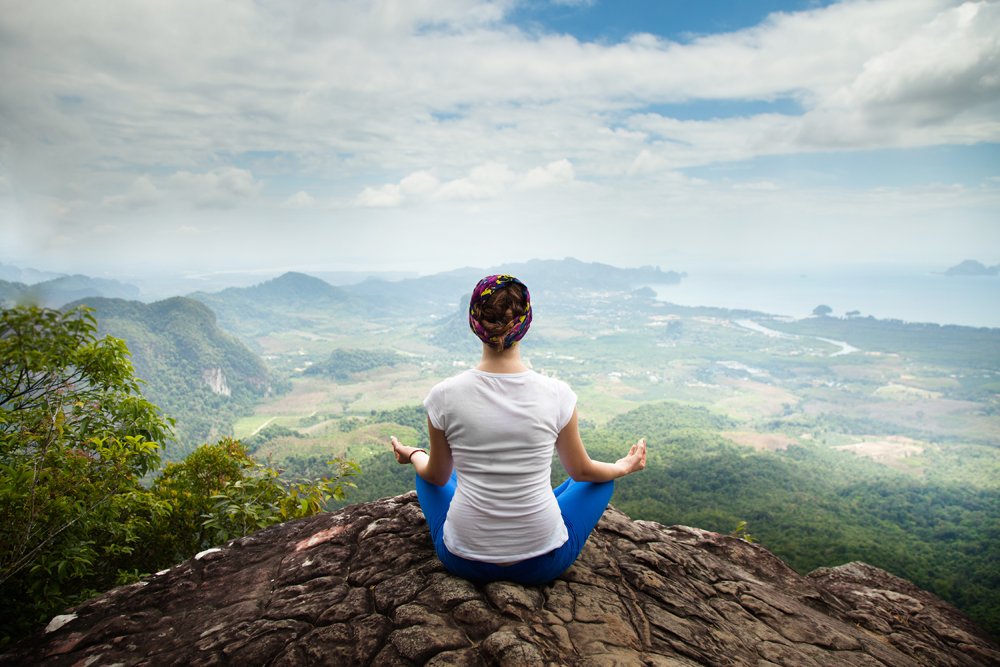 Young woman practicing yoga and meditation in mountains during luxury yoga retreat in Thailand 