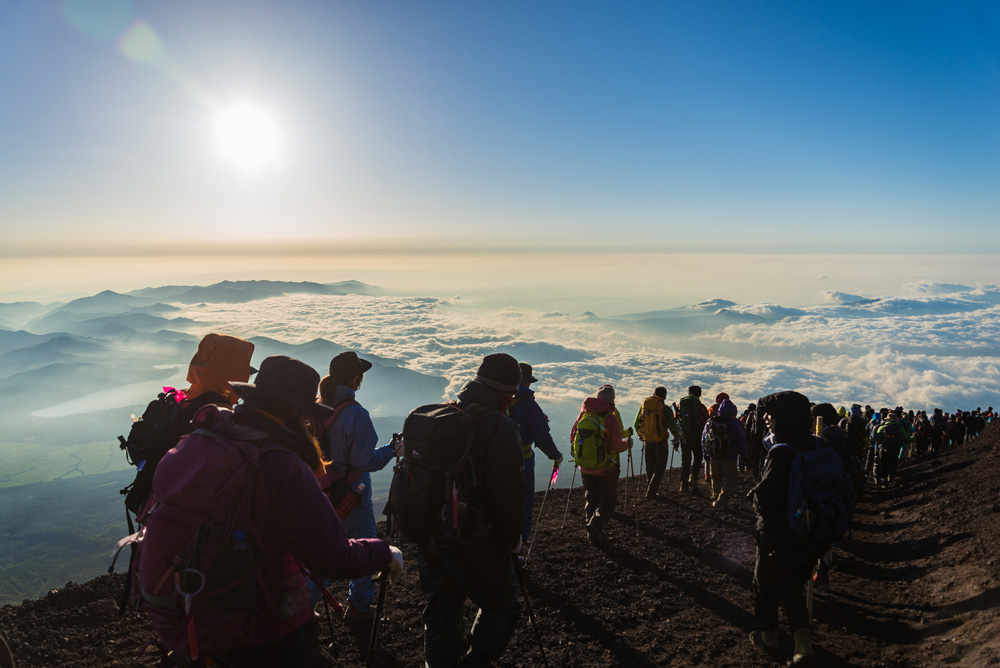 Hikers gather during sunrise on the Mount Fuji summit, Japan 