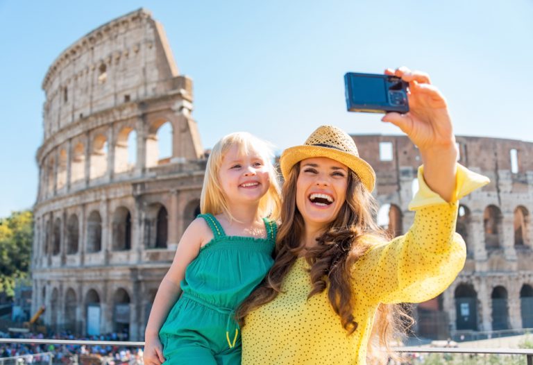 Mother and baby girl taking selfie in front of Colosseum in Rome, Italy