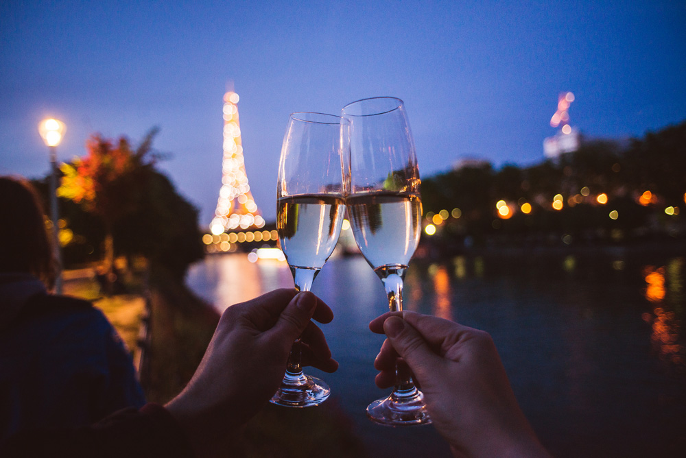 Two hands with champagne glasses in front of Eiffel Tower in Paris, France 