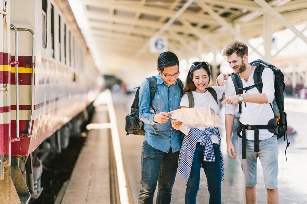 Young travellers using local map to navigate at train station platform, Asia 