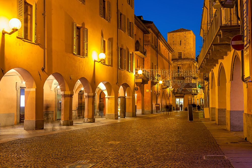 Evening view of a narrow cobblestone street in town of Alba in Piedmont, Italy 