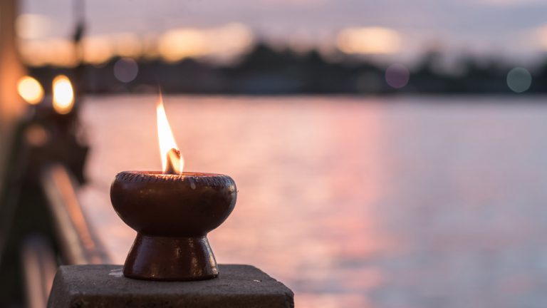 Warm candle light bokeh illumination, golden sunset sky and reflective river wave background