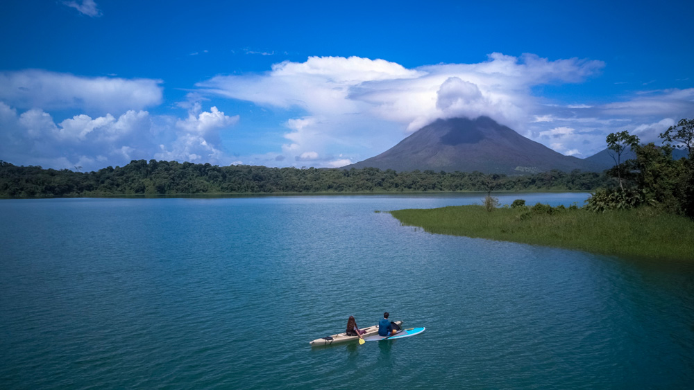 Couple paddling at Arenal Lake and admiring Arenal Volcano, Costa Rica 