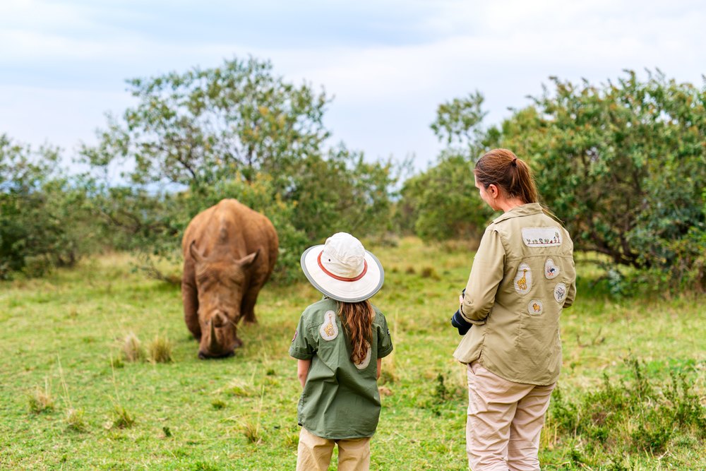 Back view of family on safari walking close to white rhino, Kenya 