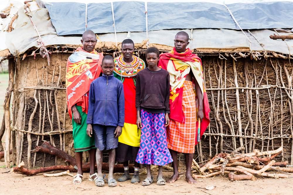 Maasai family posing in front of hut, Kenya 