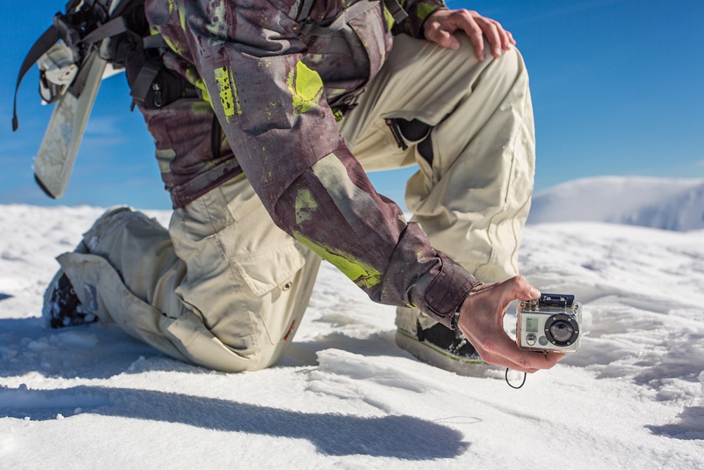 Man filming with GoPro camera in snowy mountain range 