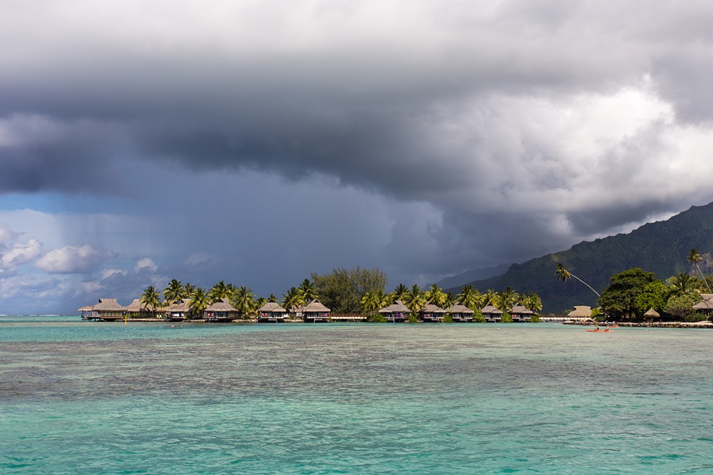 Overwater bungalows and a stormy sky and huge rain cloud, Tahiti (French Polynesia) 