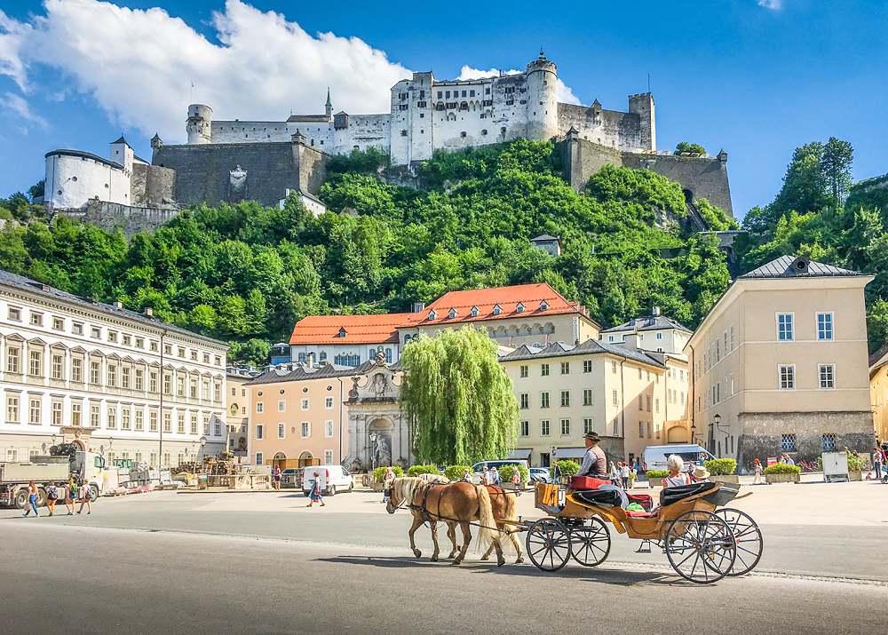 Panoramic view of Salzburg with traditional horse-drawn Fiaker carriage and Hohensalzburg Fortress, Austria 
