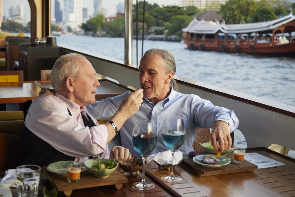 Older male couple having lunch on the Chao Phraya River.