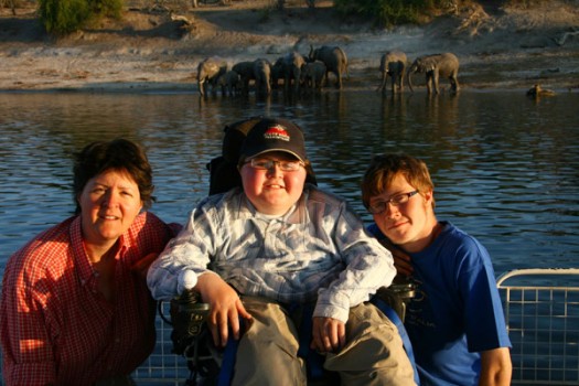 Accessible-Africa-Safaris-Family-Posing-on-Boat-in-Front-of-Elephants