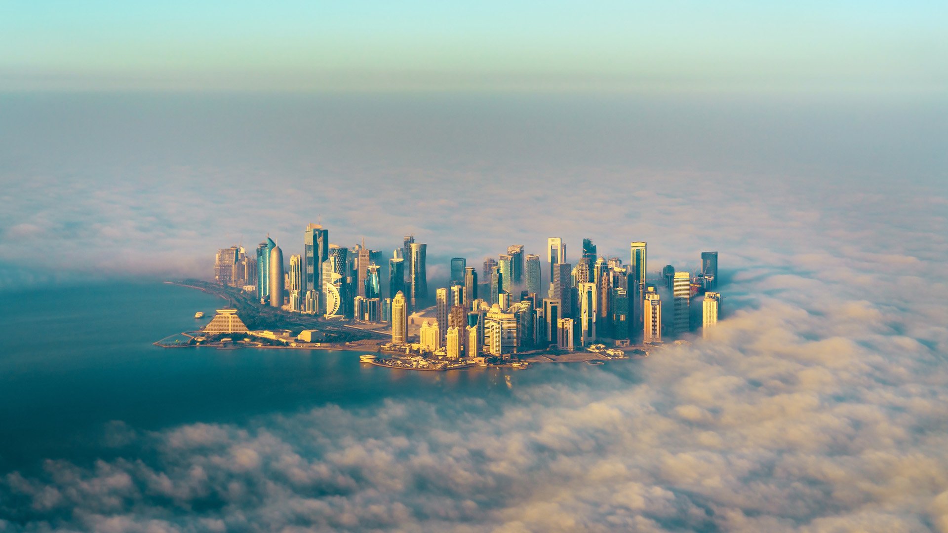 aerial view of a desert city with skyscrapers peaking through the morning fog
